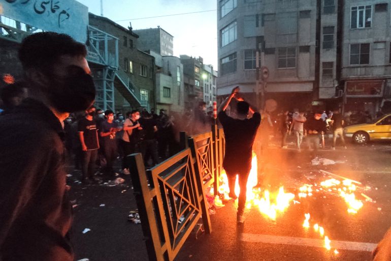 People light a fire during a protest over the death of Mahsa Amini